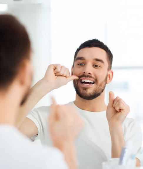 a man flossing his teeth in a bright room