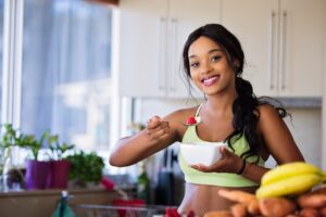 Smiling young woman eating a bowl of fruit